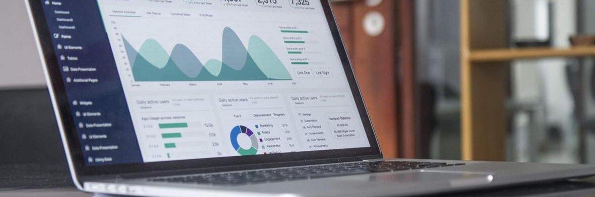 Laptop computer sitting on a desk with the screen open and displaying financial charts.